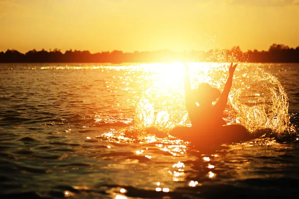 Bir adam ware şapka ve o suda yüzmek tüp oluyor. Su sıçrama yapmak için eller mi.