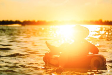 Bir adam ware şapka ve o suda yüzmek tüp oluyor. Su sıçrama yapmak için eller mi. 