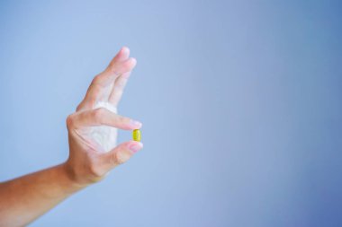 Bir yuvarlak sarı hap fotoğrafını ekrana el kapatın. Adam ilaçlar bardak su ile alır. Vitaminler, etkili ilaçlar, vücut ve ruh sağlığı için modern eczane günlük norm.