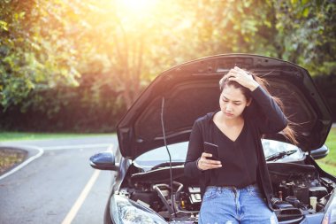 yolda bozuldu arabaya bakarken cep telefonu kullanan kadın