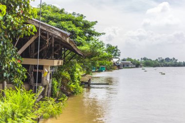 Nehir ve ağaç yakınındaki eski ahşap ev.