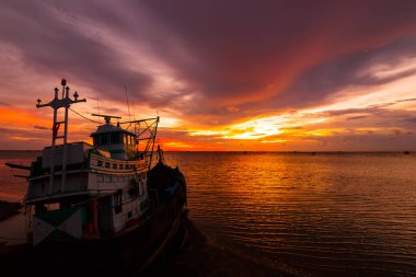 Balıkçı teknesi deniz suyunda gün batımı bulutu ve gökyüzü.