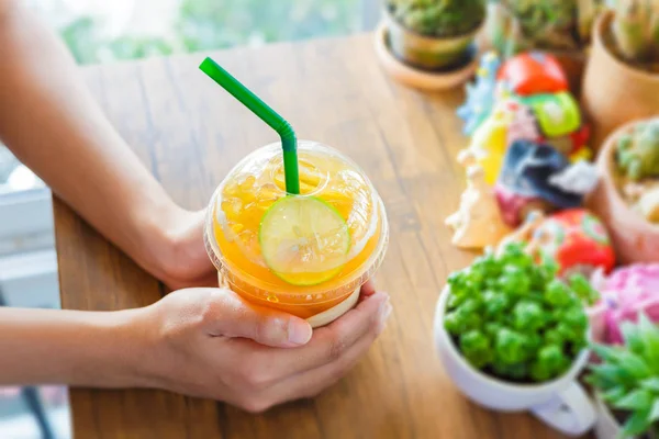 Eller ahşap masada buz çay limon tutun.