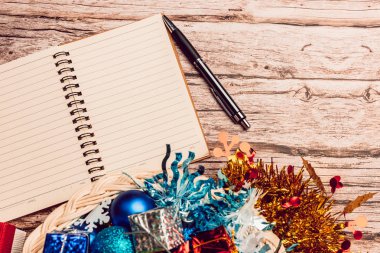 Kağıt notu kitap ve kalem ve bazı renkli biber ve ahşap masada sepet oyuncaklar ile Cristmas mevcut kutu.