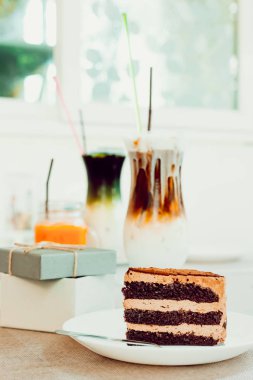 masada hediye kutusunun yanındaki masada çanak çikolatalı kek ve çatal parçası.