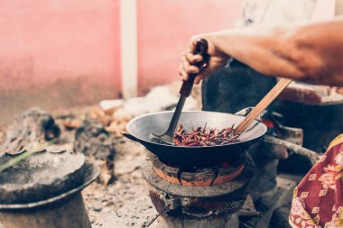 eski asyalı kadınlar Pirinç ocak yakınındaki bir tavada kurutulmuş kırmızı biber kızartma.
