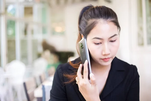 businesswomen consulting partner by phone while sitting in the coffee shop.