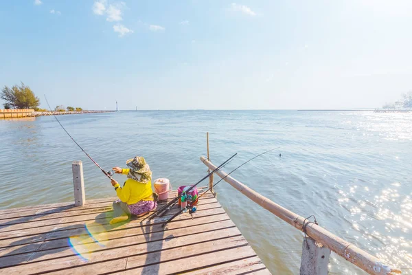 真昼の太陽の光で海の近くの地面に座っている漁師 — ストック写真
