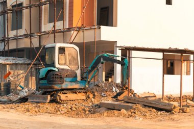 Şantiyede mini ekskavatör. Ekskavatör evin çevresindeki araziyi düzenler.
