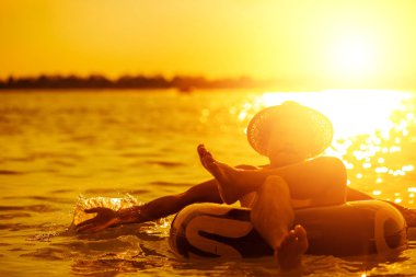 Bir adam şapka takar ve yüzme tüpüyle suda yüzer..