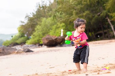 Bir çocuk plajda oyuncak ve kum oynamak.