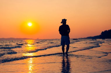 Genç adam sahilde yürüyor. seyahat ve rahatlama konsepti.