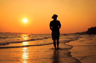 Genç adam sahilde yürüyor. seyahat ve rahatlama konsepti.
