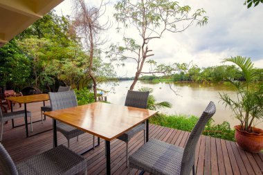 Otel, tatil teras nehir üzerinde boş masa ve sandalyeler.