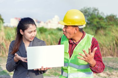Sert şapkalı ve üniformalı, genç bir kadınla birlikte erkekler. Mimarlar, mühendislerden oluşan ekip çalışmaları tartışıyor.