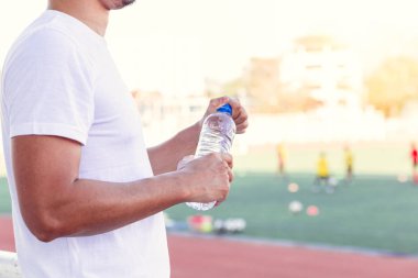 Susamış adam spor stadyumunda saf su şişesi açmak.