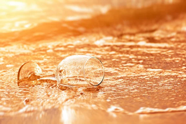 Hand hold glass and water flow at sunset.