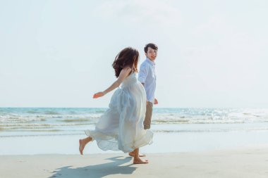 Kumsalda koşan ve yürüyen romantik bir çift. Aşık bir adam ve kadın. İnsanlar seyahat konsepti.