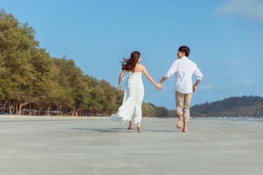 Kumsalda koşan ve yürüyen romantik bir çift. Aşık bir adam ve kadın. İnsanlar seyahat konsepti.