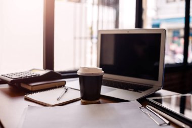 Ahşap masa üzerinde dizüstü bilgisayarı, hesap makinesi, kitabı ve belgesi olan ofis işyeri