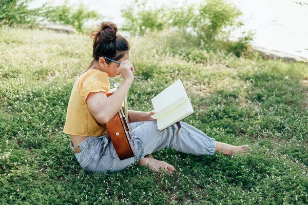 songwriter create and writing notes,lyrics in the book on grass at parks beside the sea and building city background.
