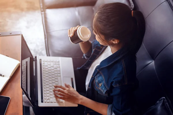 Mujer Joven Sentada Sofá Cafetería Tomando Café Mientras Trabaja Computadora — Foto de Stock