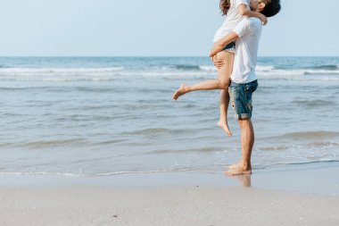 Romantik çift kumsalda sevişiyor ve sarılıyor.