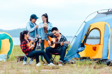 Bir grup arkadaş kamp yapıyor ve gitar çalıyorlar. Kamp ve müzik gitar konsepti.