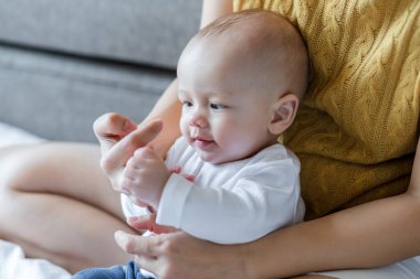Mutlu anne ve bebek evdeki yatakta birlikte oynuyorlar. Aile sevgisi kavramı.