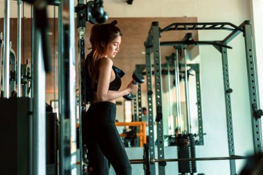 Fitness kızı spor salonunda dambılı kaldırıyor. Spor ve kas konsepti.
