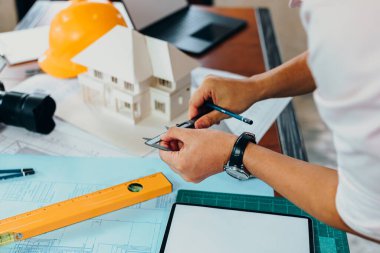 Mühendislerin elleri, çalışma ve çizim planı ve ev modelini kontrol etmek için vernier kalibre ve kalemi tutuyor..