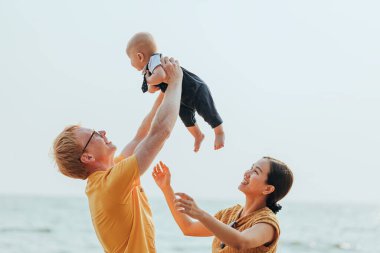 Kumsalda mutlu bir aile. Baba, anne ve bebek yaz tatilinde eğleniyorlar. Tatil seyahati kavramı