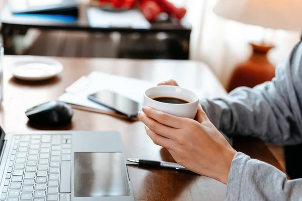 Kvinde Der Arbejder Laptop Holde Kop Kaffe Mens Sidder Arbejdspladsen - Stock-foto