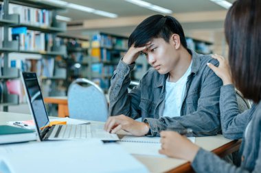 Öğrencilerin başı ağrıyor, strese giriyor, kütüphanede kitap okumak için endişeleniyorlar. Eğitim kavramı.