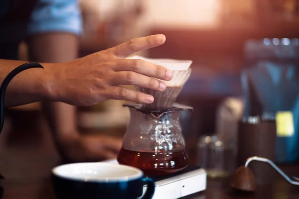 Barista measuring coffee drip with glass mug