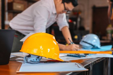 İnşaat alanındaki masada güvenlik kaskları var. Mimar, Mühendis ve işadamı planlama geçmişini okudu. 
