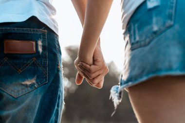 Romantik çift el ele tutuşup sahilde yürüyor. Aşık bir adam ve kadın.