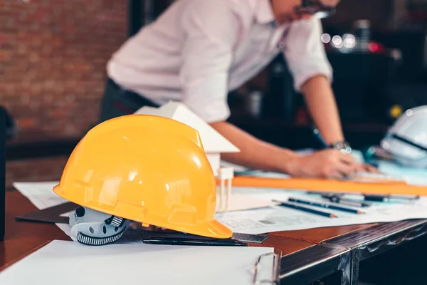 現場建設のテーブルの上の安全ヘルメット 建築家 エンジニア ビジネスマンは計画の背景を読む — ストック写真