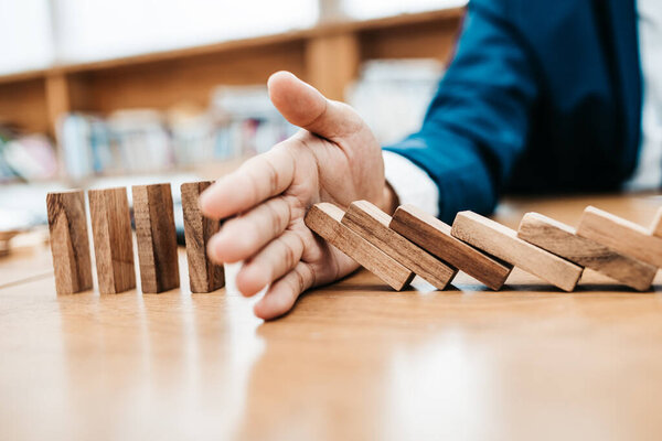 Businessman protect wooden block fall to planning and strategy in risk to business Alternative and prevent.
