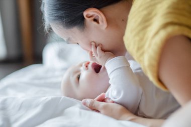 Mutlu bir anne öpücüğü ve evde tatlı bir bebekle oynaşması. Aile sevgisi ve bakım. Aile bebeği, yeni doğan kavramı.