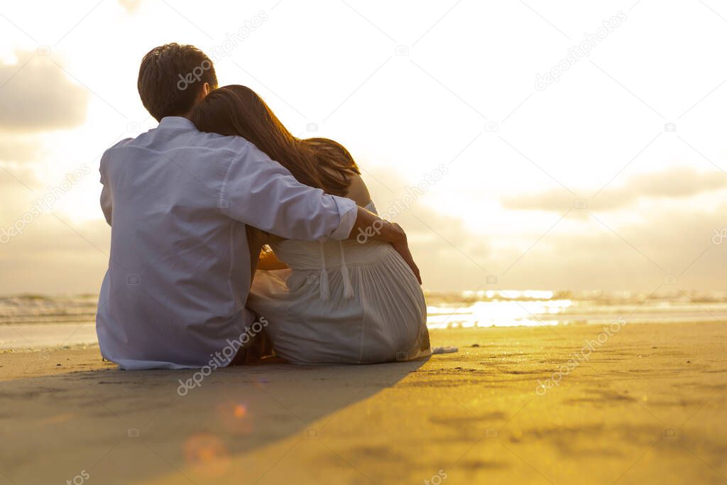 Couple in love watching sunset together on the beach travel summer holidays. People romance concept.
