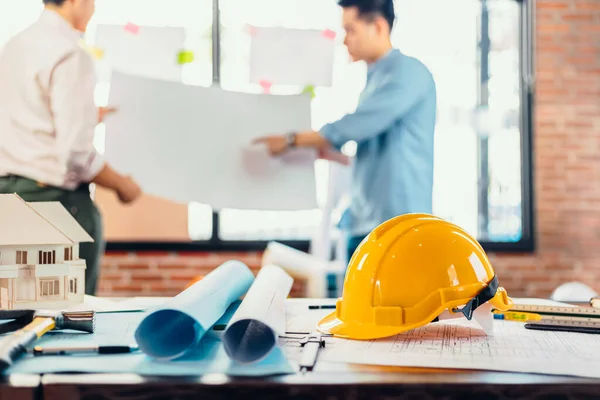 建筑工地时 安全头盔放在桌子上 建筑师 工程师和商人阅读规划背景 — 图库照片