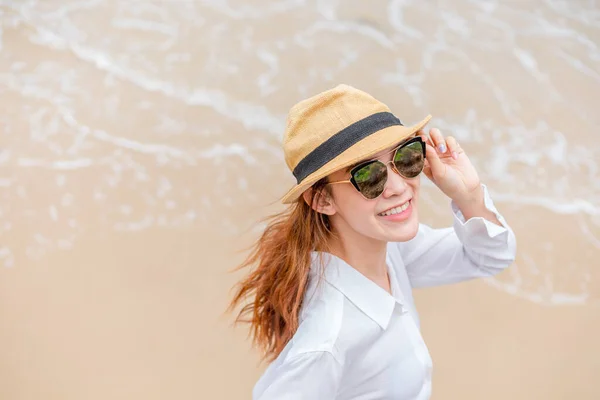 smiling young woman in sun hat and waring sun glasses on the  beach. summer, holidays, vacation, travel concept