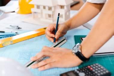 Bir binayı işaret eden bir kalem tutan mühendisler, inşaatçılar için ayrıntılı bir kılavuz olarak çıkış planı çiziyorlar. Mühendis tasarımı ve yazma planı.