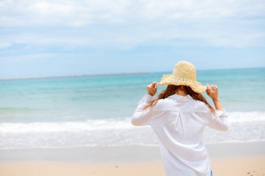 Kumsalda güneş şapkası takan genç bir kadın. yaz, tatiller, tatil, seyahat kavramı