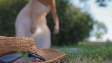 uzun saçlı gülümseyen kız diş telleri Bayan yalanlarla çimenlerin üzerinde çalışan karşı ağır çekim hasır şapka güneş gözlüğü açar dizüstü bilgisayar