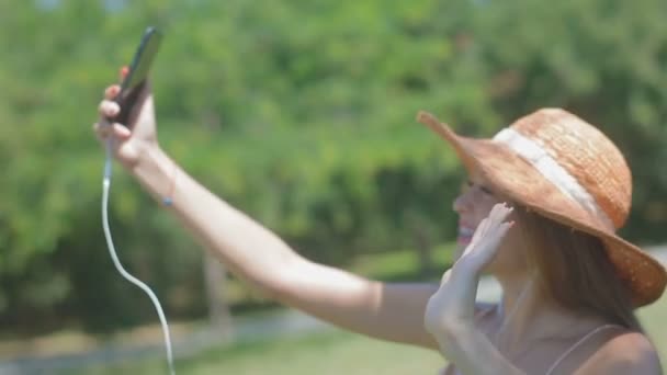 慢动作漂亮的女士与括号在黄色草帽举行手机以上的头微笑旋转波手在阳光明媚的日子 — 图库视频影像