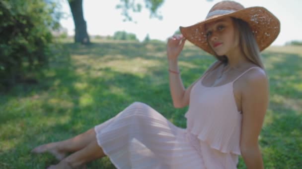 迷人的金发女士在现代草帽坐在草地上摆姿势 — 图库视频影像