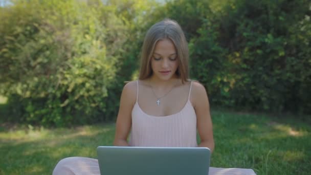 长头发的妇女坐在草地上与笔记本电脑 — 图库视频影像
