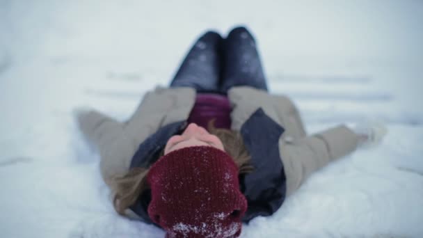 微笑的女人躺在雪背上 扔雪花 寒冷的寒假 — 图库视频影像